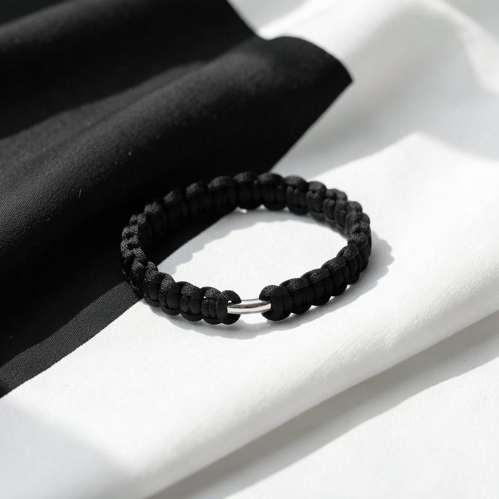 A braided black cord bracelet on folded fabric