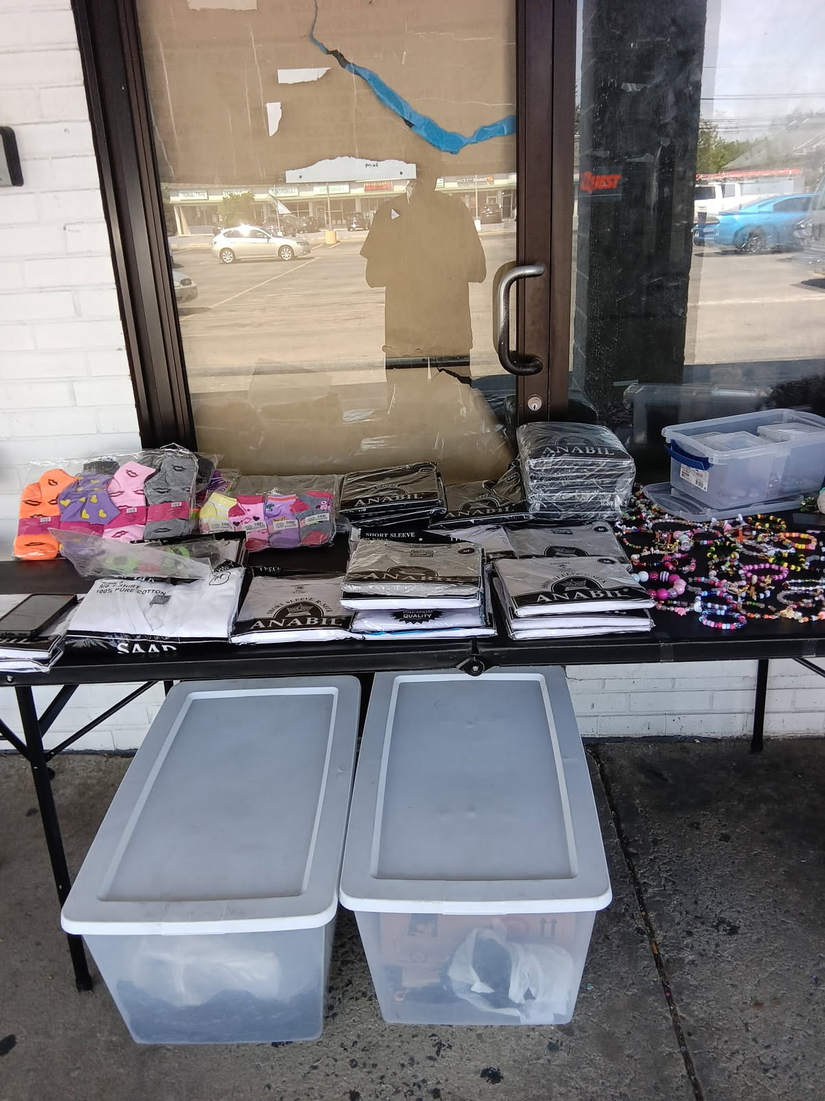 Chappell’s vendor table in Brookhaven — folded tees, kids’ socks and the bracelet bin